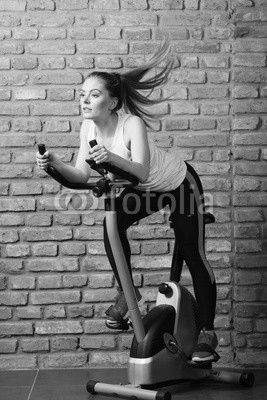 Active woman using exercise bike at the gym.