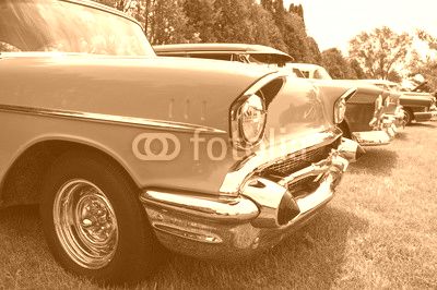 Vintage hot rods at a car show front ends. A row of awesome hot rods at a car show restored front ends with headlights exposed engines and grilles. Row of cars at a car show.