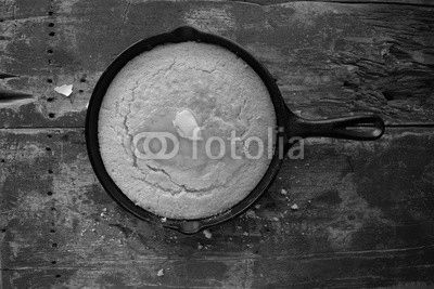 Yellow Cornbread in cast iron skillet on rustic wood table