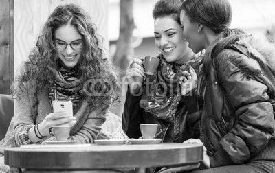 Women in cafe showing pictures on smart phone