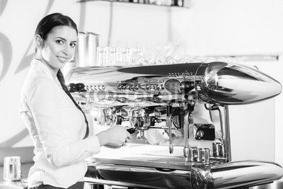 Young waitress using an automatic coffee machine