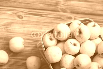 Golden apples in a basket on a wooden background