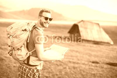 Young redhair man on mountain hiking holding a map