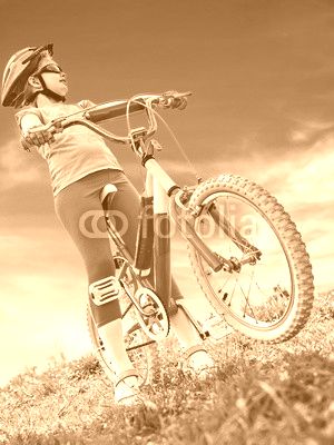 Child traveling bicycle in summer park. Children road bike for running on green grass. Bottom view aganist sky blue. Cycling trip is good for health.