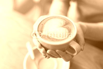 lady's hands holding cup with sth heart-shaped