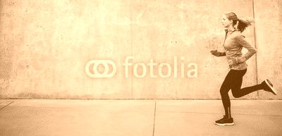 Young woman running on sidewalk in morning