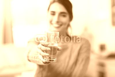 Young woman showing drinking glass with water