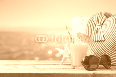 Summer holiday vacation concept with orange juice, hat and sunglasses over sea beach background