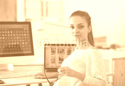 Young woman working in office, sitting at desk
