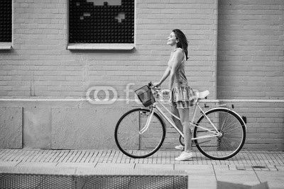 Happy woman with bike standing agains brick building
