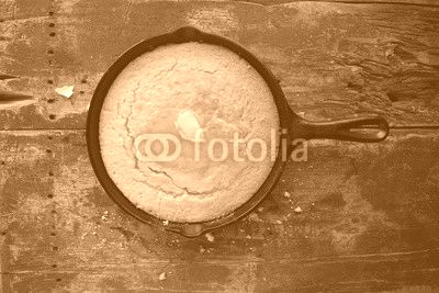 Yellow Cornbread in cast iron skillet on rustic wood table