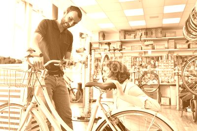Mechaniker mit Kundin in einem Fahrradladen - Reparatur Fahrrad in der Werkstatt