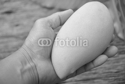 Delicious ripe mango with green leaf in hand  on wooden background.