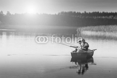 father and son catch fish from a boat at sunset