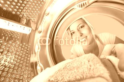Smiling Woman Inserting Clothes In Washing Machine