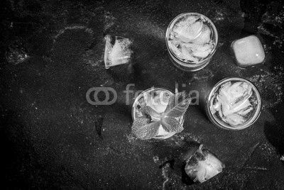 Alcohol cocktail made from golden tequila with ice cubes and mint. On a black concrete table. Copy space top view