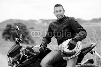handsome young man biker with white helmet riding black motorcycle