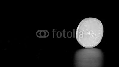 rolling orange fruit slice on black background, slow motion