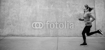 Young woman running on sidewalk in morning