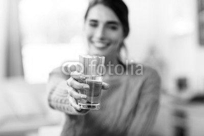 Young woman showing drinking glass with water