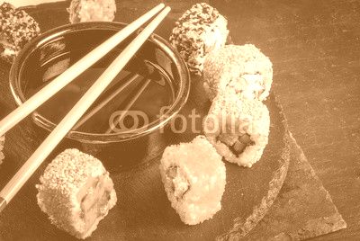 Concept of Japanese food: sticks and sushi, soy sauce and pickled ginger on a black slate stone table. Top view copy space