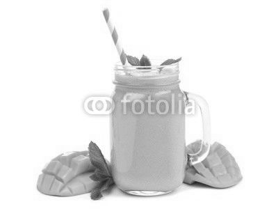 Mango coconut smoothie in a mason jar glass with mint and straw isolated on white