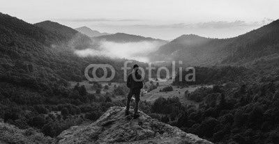 Man standing on top of cliff at sunset