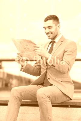 young smiling businessman newspaper outdoors