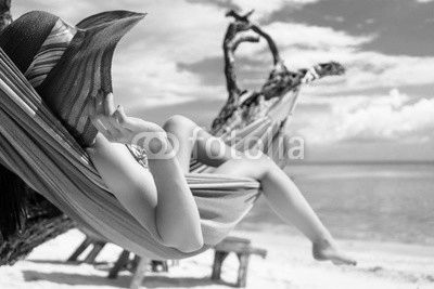 Frau im Urlaub am Strand entspannt in Hängematte am Meer