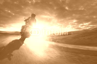 Motorrad fährt  durch eine Kurve bei Sonnenuntergang