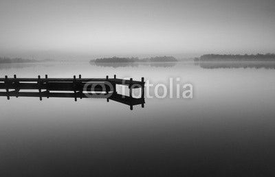 Jetty during a tranquil, foggy dawn at a lake.