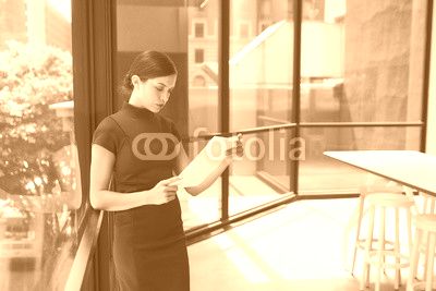 Young white businesswoman reading document in modern office