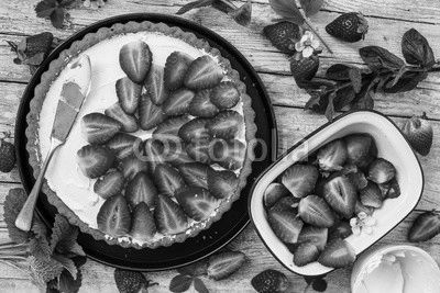 Delicious sponge cake with fresh strawberries on a wooden background.
