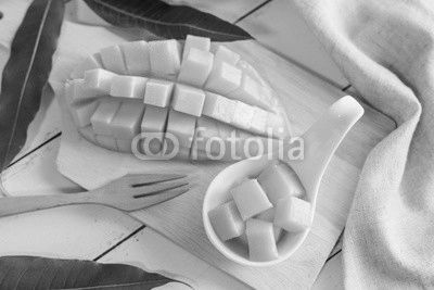 Ripe mango fruit and mango cubes on white wooden table
