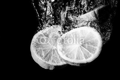 Lemon slice splashing into water.