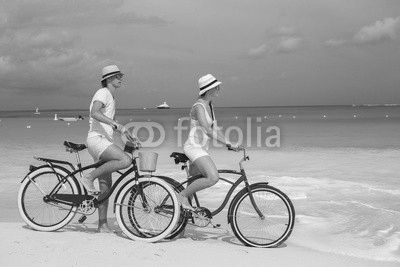 Young happy couple riding bikes on white tropical beach