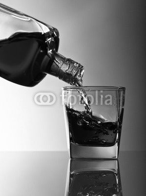 bottle and glass of whiskey on a glass table