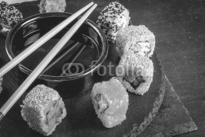 Concept of Japanese food: sticks and sushi, soy sauce and pickled ginger on a black slate stone table. Top view copy space