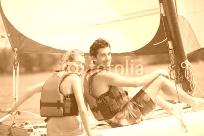 young couple steering a catamaran