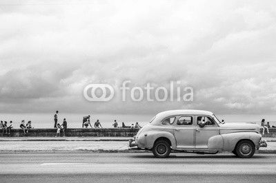 HAVANA, CUBA - MAY 18, 2011: Classic vintage American car serving as taxi drives along the seafront Malecon, a popular place for socializing in Central Havana.