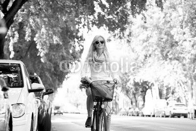 She goes everywhere by bike. Full length shot of a young woman in the street with a bicycle.