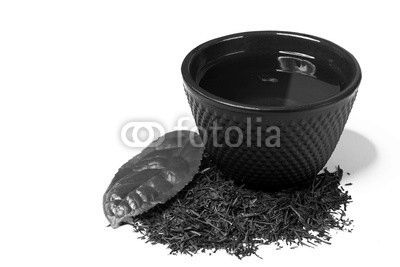 Cup and heap of green shincha tea with leaf.