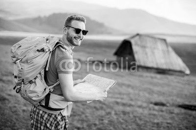 Young redhair man on mountain hiking holding a map
