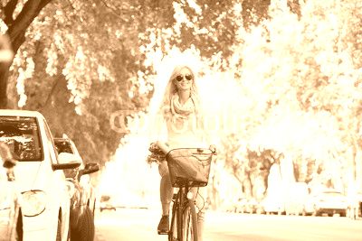 She goes everywhere by bike. Full length shot of a young woman in the street with a bicycle.