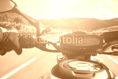 Motorradfahrer fährt auf Straße im Sommer