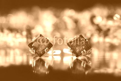 Closeup silver earrings rhombus with authentic natural baltic amber on black  surface on background of orange amber