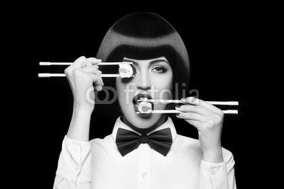 Beautiful woman eating sushi with chopsticks