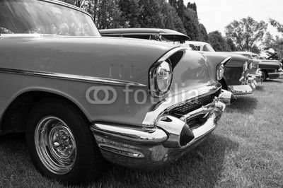 Vintage hot rods at a car show front ends. A row of awesome hot rods at a car show restored front ends with headlights exposed engines and grilles. Row of cars at a car show.