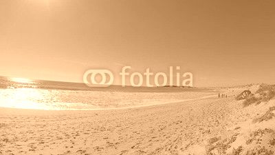 Unrecognizable people on the beach, with the Trafalgar lighthouse in the background, on the coast of Cadiz, Spain