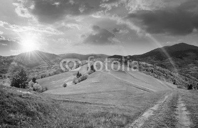 fence on hillside meadow in mountain at sunset